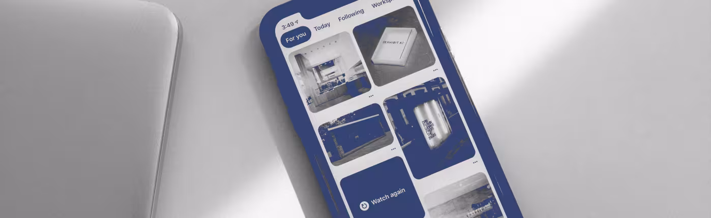 Smartphone showing an app with blue thumbnails, beside a laptop on a light grey desk