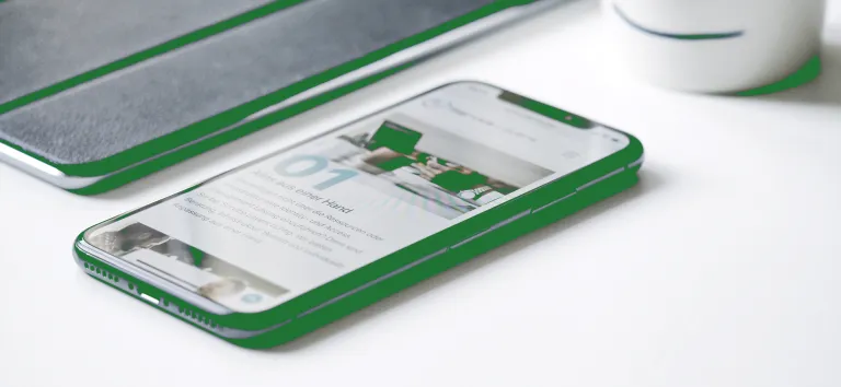 Smartphone and tablet with green edges on a white table, a website on screen