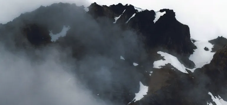 Snowy rocky peak rising out of the mist