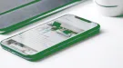 Smartphone and tablet with green edges on a white table, a website on screen
