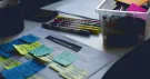 Notes adhésives colorées sur une feuille de travail, feutres et boîte de fournitures sur un bureau