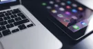 Ordinateur portable et iPad affichant ses icônes d’applications, en gros plan sur fond sombre