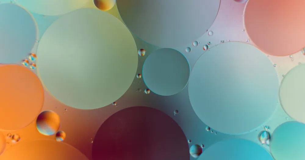 Bulles d’huile sur l’eau aux reflets orange, rose et turquoise, en gros plan