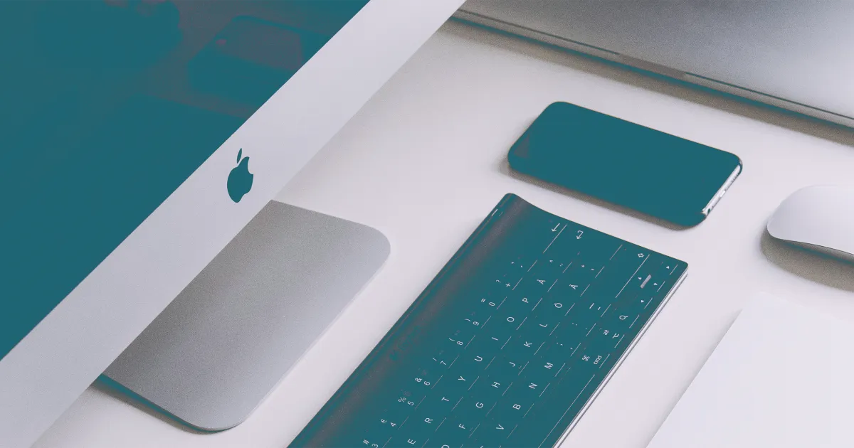 iMac, clavier et iPhone teintés bleu sarcelle sur un bureau blanc, une souris à droite